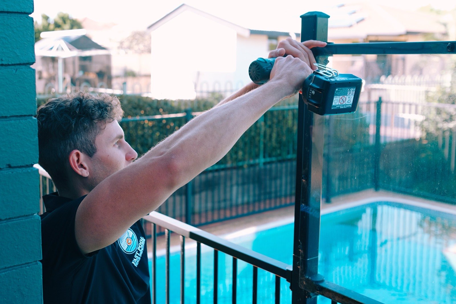 Inspector adjusting a pool gate latch with a drill during an inspection