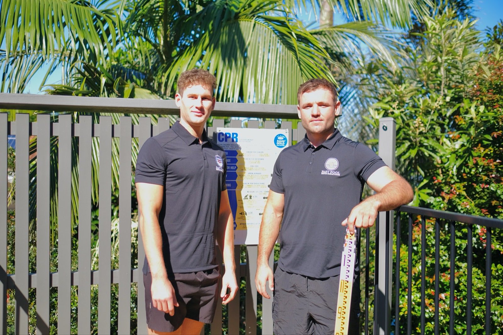 The two Fast Pool Fence Inspections inspectors beside a pool fence with a CPR sign